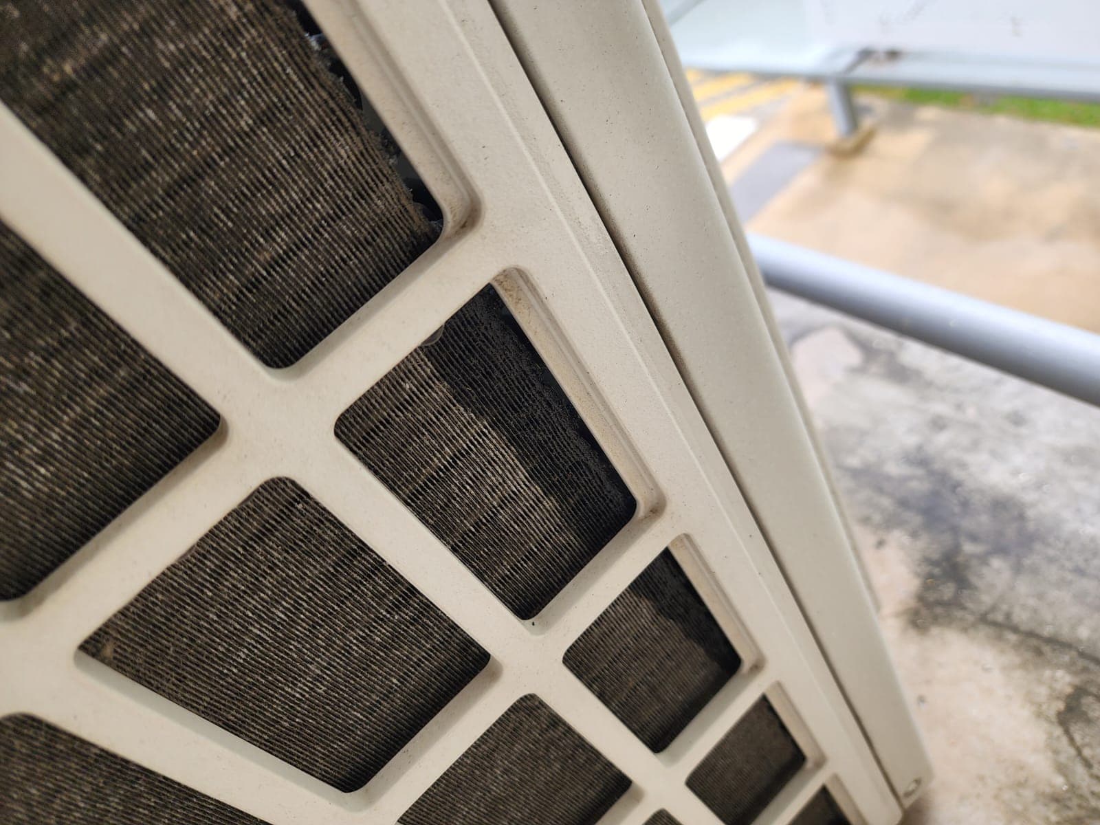 Dust-caked outdoor condenser coil on HDB corridor ledge