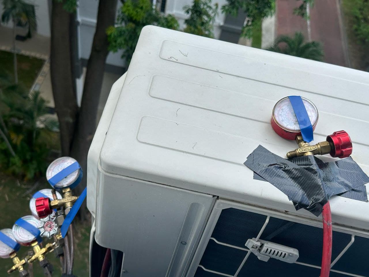 Outdoor condenser unit connected to manifold gauges for refrigerant pressure testing