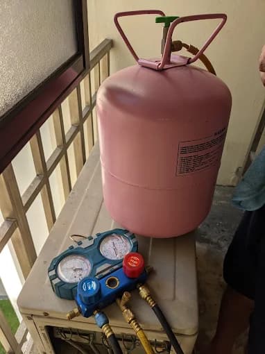 R410A refrigerant canister and manifold gauges ready for a measured aircon top-up.