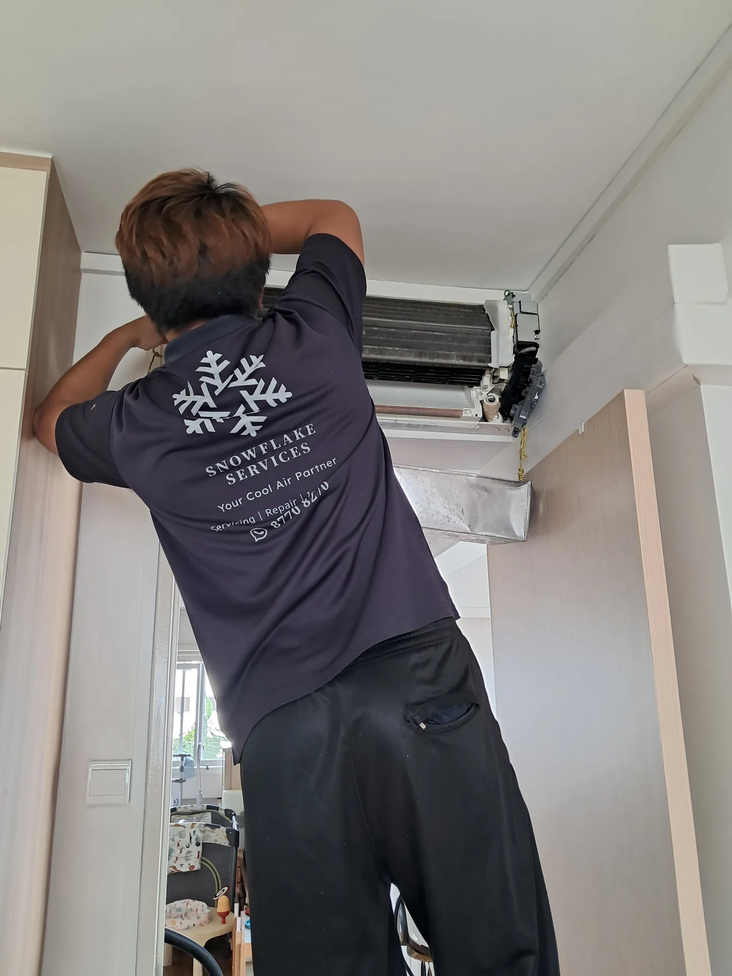 Technician servicing a wall-mounted aircon unit with its cover removed