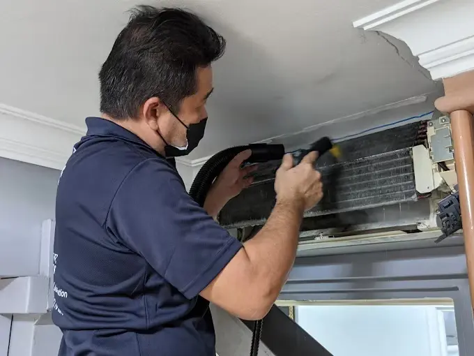 Technician brushing the coil of an opened indoor unit