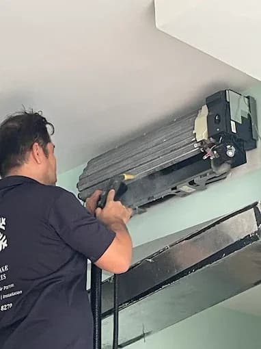 Technician cleaning an indoor fan coil with the casing removed