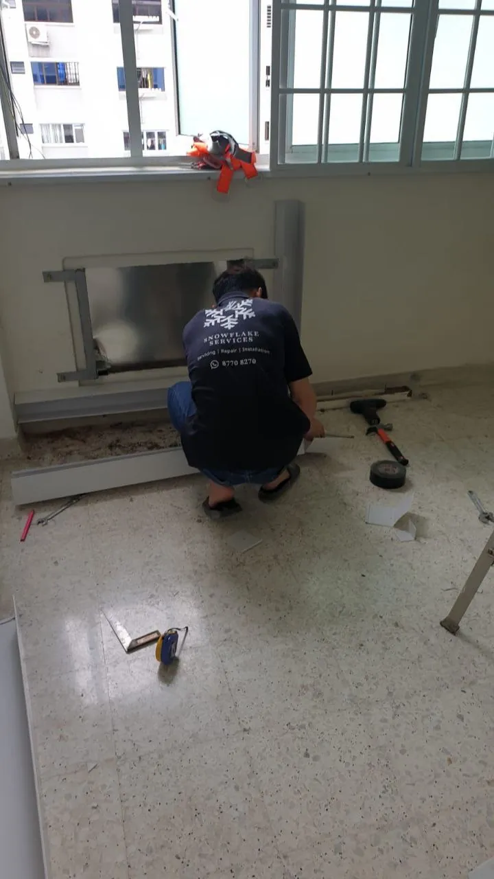 Technician preparing the wall for an aircon installation in an HDB flat