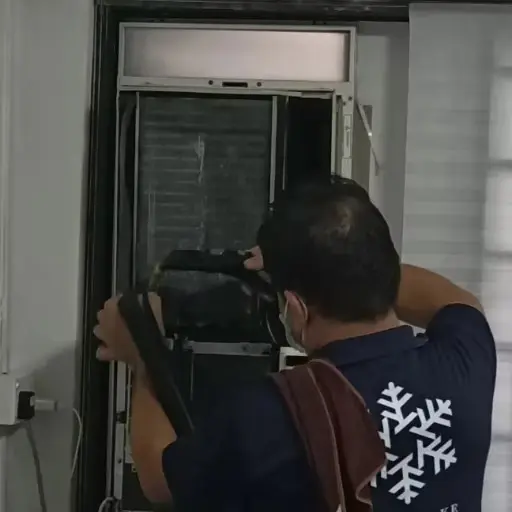 Technician servicing a floor-standing aircon unit