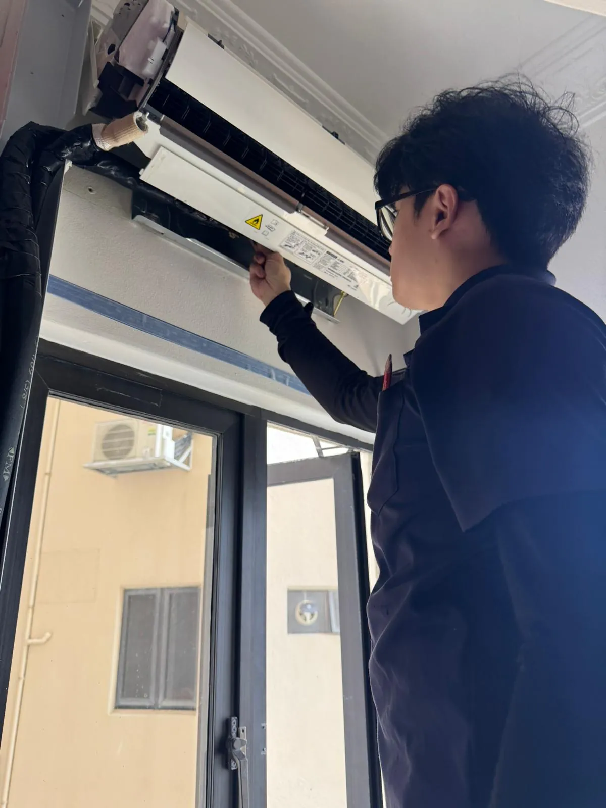 Technician inspecting the internals of a wall-mounted aircon unit