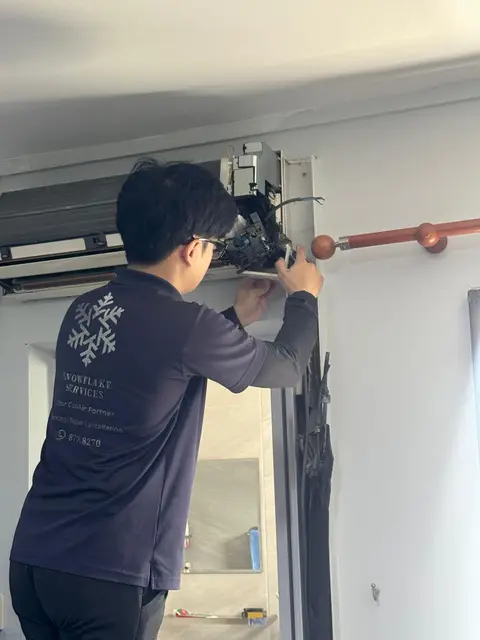 Technician at an opened wall unit with electrical box exposed