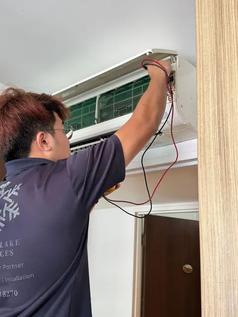 Technician probing wall unit electrics with meter leads