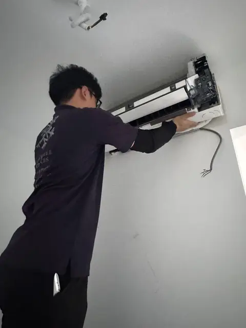 Technician removing the front of a wall unit with loose wires hanging