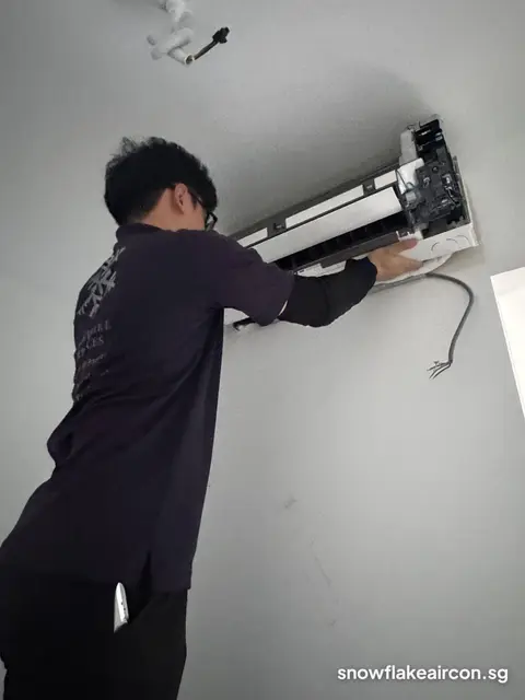 Technician removing the front of a wall unit with loose wires hanging
