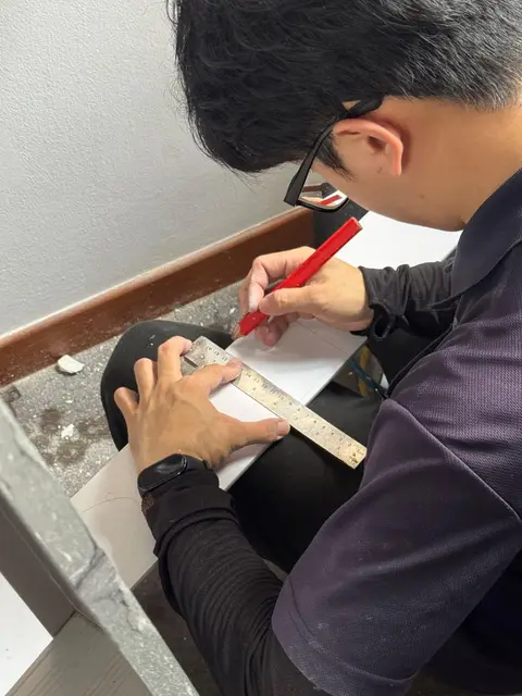 Technician marking a measurement on paper with a ruler
