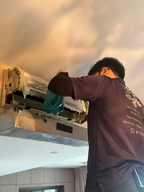 Technician with cover sheet on a ceiling-mounted unit
