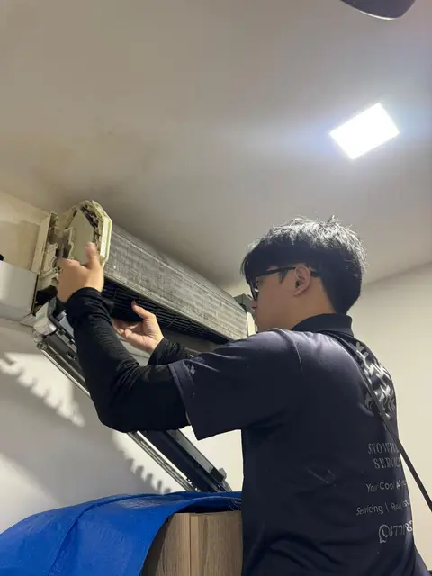 Technician lifting out a dusty indoor coil from a wall unit