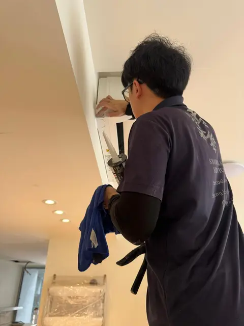 Technician wiping a wall unit with a cloth while holding a sealant gun